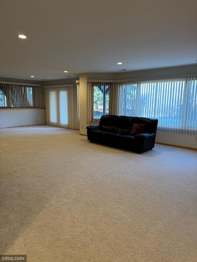 living area with recessed lighting, visible vents, baseboards, and light carpet