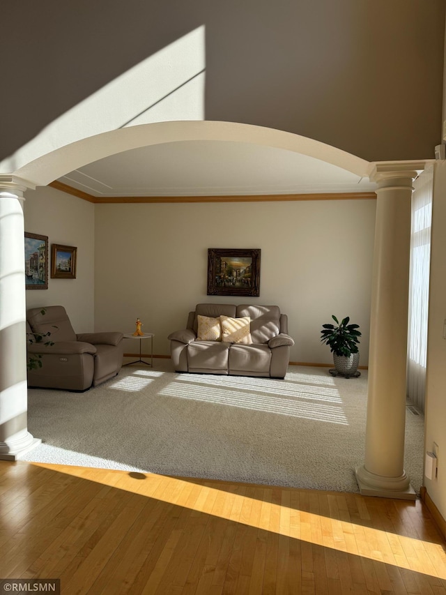 living room with hardwood / wood-style flooring, arched walkways, crown molding, and ornate columns