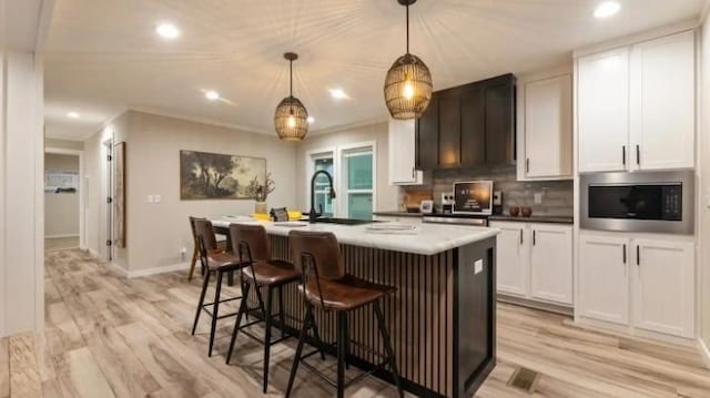 000 Pine Ave S, Sandstone, MN 55072 - kitchen featuring stainless steel microwave, an island with sink, tasteful backsplash, white cabinetry, and recessed lighting