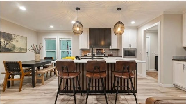 000 Pine Ave S, Sandstone, MN 55072 - kitchen featuring stainless steel microwave, light wood finished floors, white cabinetry, crown molding, and pendant lighting