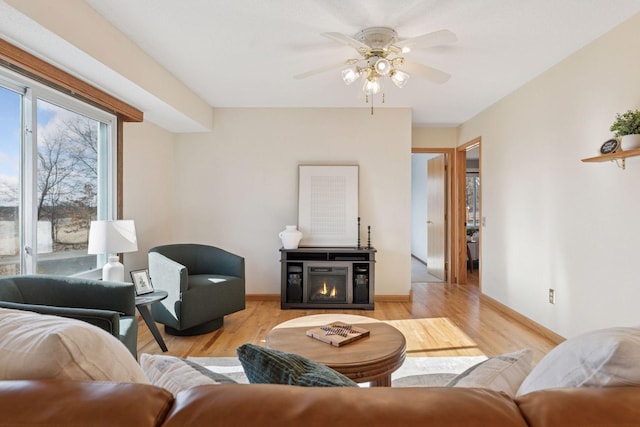 828 143rd St, Garfield Twp, WI 54001 - living area featuring a ceiling fan, light wood-style flooring, baseboards, and a glass covered fireplace