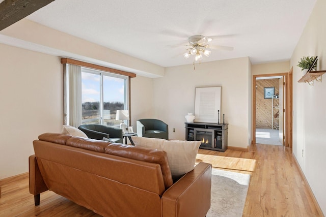 828 143rd St, Garfield Twp, WI 54001 - living area featuring a glass covered fireplace, light wood finished floors, a ceiling fan, and baseboards