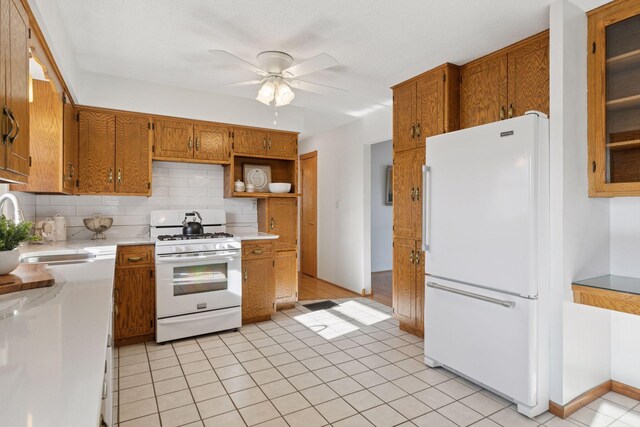 828 143rd St, Garfield Twp, WI 54001 - kitchen with white appliances, a sink, light countertops, decorative backsplash, and brown cabinetry
