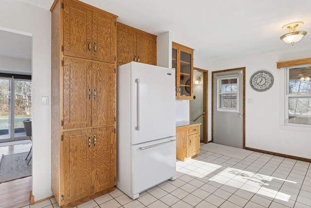 828 143rd St, Garfield Twp, WI 54001 - kitchen with freestanding refrigerator, glass insert cabinets, brown cabinets, baseboards, and light tile patterned floors