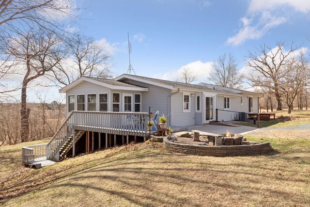 828 143rd St, Garfield Twp, WI 54001 - back of property with an outdoor fire pit, a wooden deck, a sunroom, and a lawn