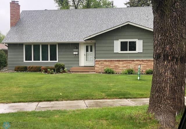 2902 3rd St N, Fargo, ND 58102 - view of front of house with a chimney, brick siding, a front lawn, and a shingled roof