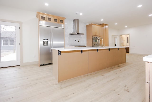 123 River View Rd, Ottertail, MN 56571 - kitchen with wall chimney range hood, built in refrigerator, light wood finished floors, light brown cabinetry, and a large island