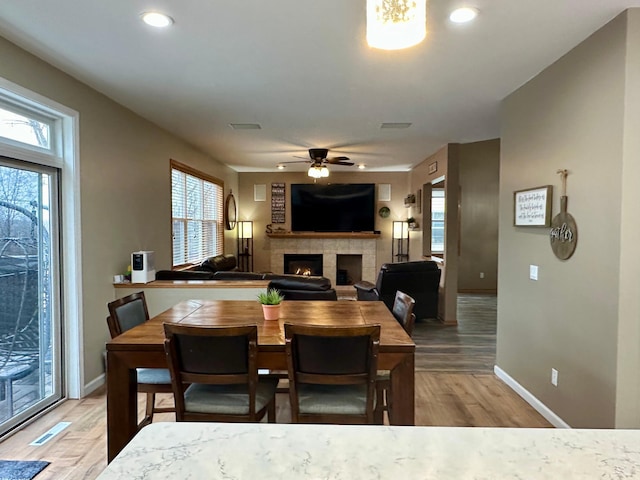 dining room featuring plenty of natural light, baseboards, a ceiling fan, and a fireplace