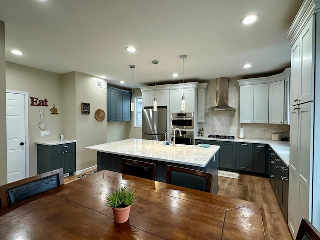 kitchen with recessed lighting, decorative light fixtures, wall chimney exhaust hood, tasteful backsplash, and appliances with stainless steel finishes