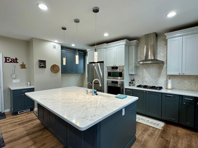 kitchen featuring wall chimney exhaust hood, a sink, appliances with stainless steel finishes, and dark wood-style flooring