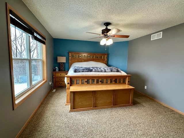 bedroom featuring a ceiling fan, a textured ceiling, light carpet, baseboards, and visible vents
