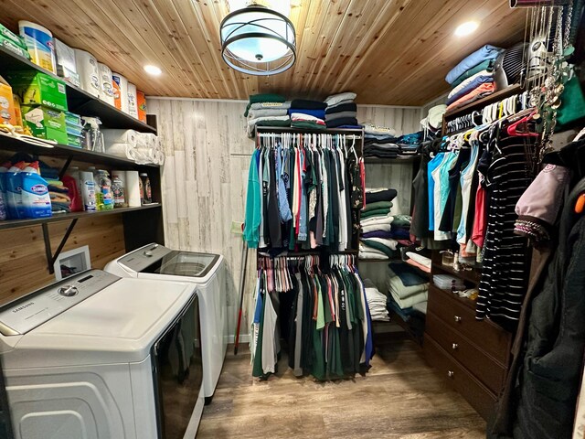 laundry room with wood walls, laundry area, wood finished floors, wooden ceiling, and washing machine and dryer