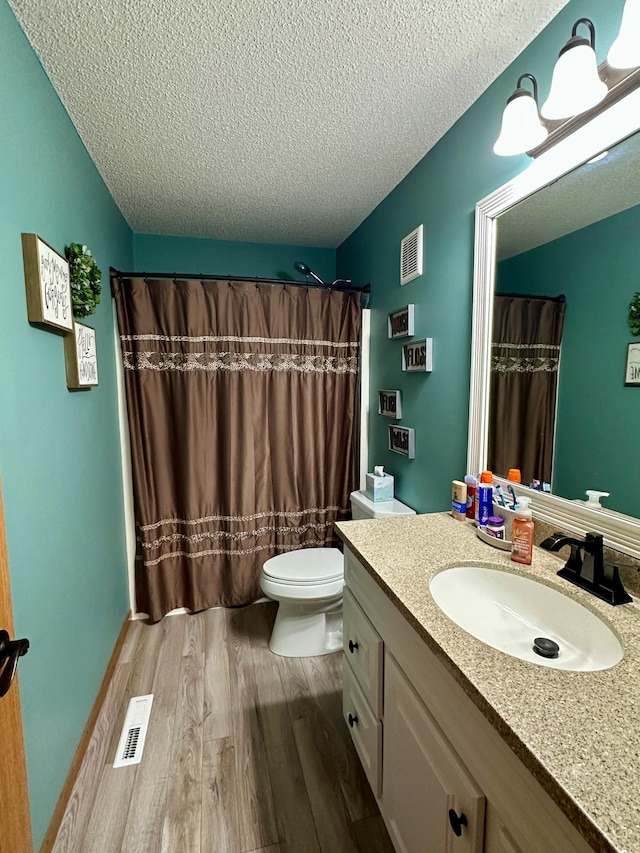 bathroom featuring wood finished floors, visible vents, and a textured ceiling