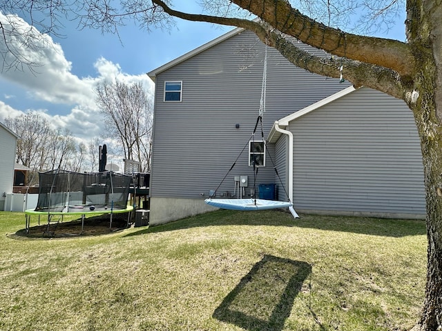 back of house with a yard and a trampoline