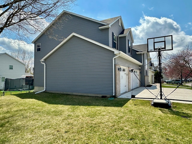 view of property exterior featuring a yard, a trampoline, and fence