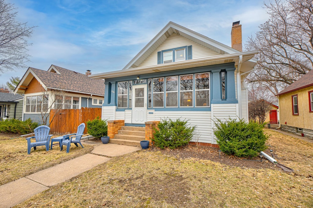 bungalow-style house featuring fence, a sunroom, and a chimney