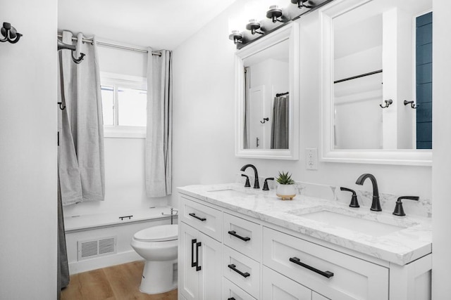 493 Rolls Rd, New Brighton, MN 55112 - full bathroom with toilet, double vanity, wood finished floors, and a shower with curtain