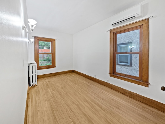 3441 Portland Ave Unit 2, Minneapolis, MN 55407 - empty room with a wall unit AC, radiator heating unit, light wood-type flooring, and baseboards