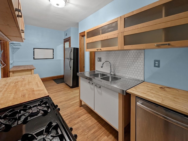 3441 Portland Ave Unit 2, Minneapolis, MN 55407 - kitchen with stainless steel appliances, a sink, stainless steel countertops, backsplash, and light wood finished floors