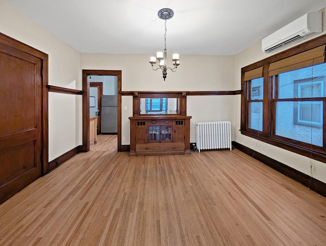 3441 Portland Ave Unit 2, Minneapolis, MN 55407 - unfurnished dining area with radiator, a wall mounted air conditioner, light wood-style flooring, baseboards, and a chandelier