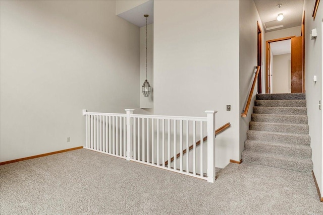 stairway featuring baseboards and carpet