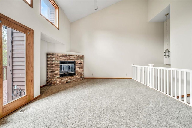 unfurnished living room with a brick fireplace, carpet flooring, high vaulted ceiling, and a healthy amount of sunlight