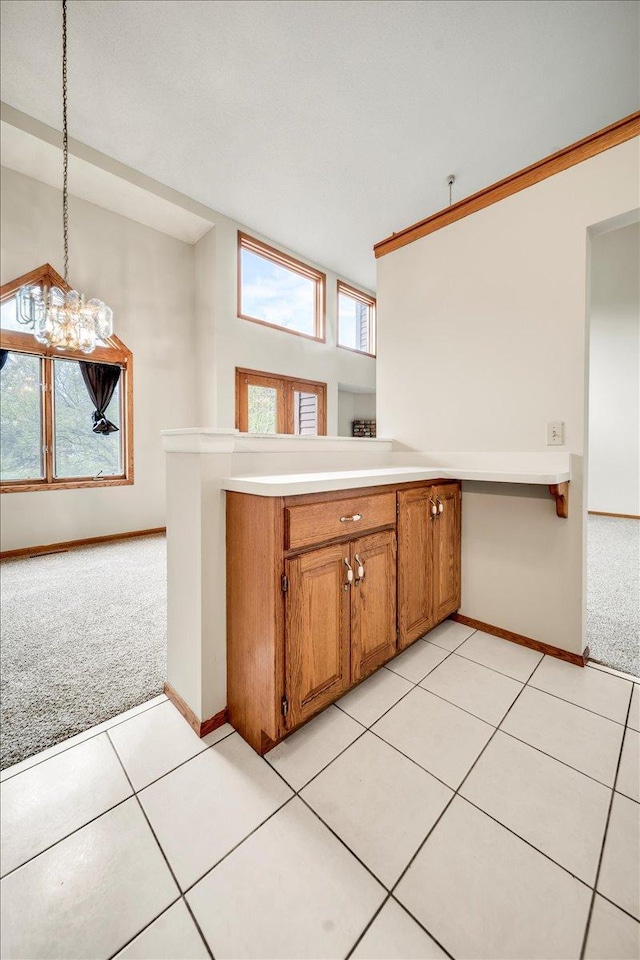 kitchen with light carpet, baseboards, brown cabinets, light countertops, and decorative light fixtures