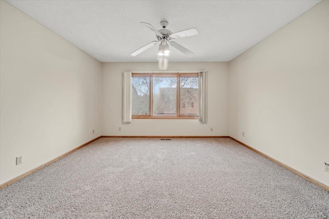 carpeted spare room featuring a textured ceiling, visible vents, baseboards, and ceiling fan