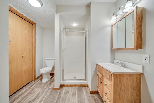 bathroom featuring vanity, wood finished floors, a shower stall, and toilet