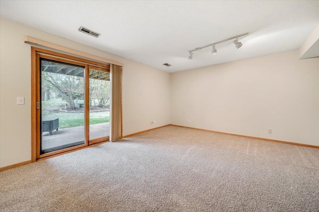 spare room with light colored carpet, rail lighting, baseboards, and visible vents