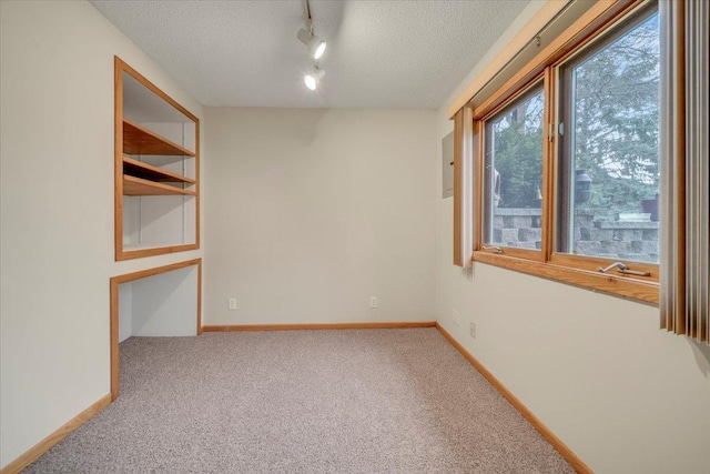 unfurnished room with track lighting, baseboards, a textured ceiling, and carpet