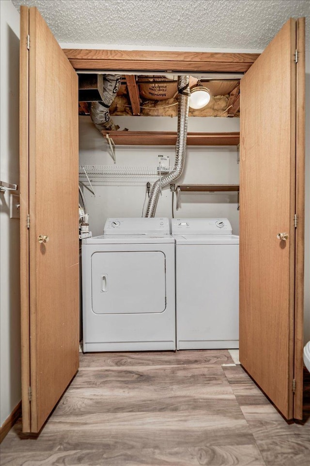 washroom with washing machine and dryer, a textured ceiling, light wood finished floors, and laundry area