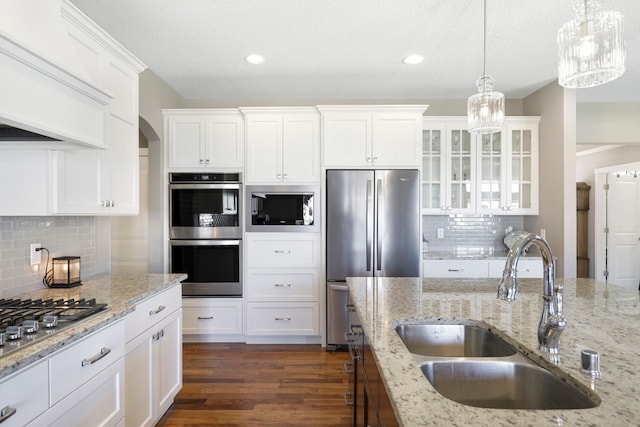 kitchen featuring white cabinets, stainless steel appliances, an inviting chandelier, and a sink