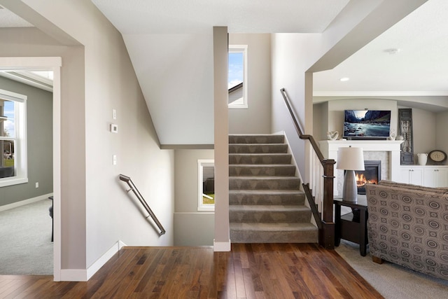 stairs featuring baseboards, recessed lighting, a glass covered fireplace, and hardwood / wood-style flooring
