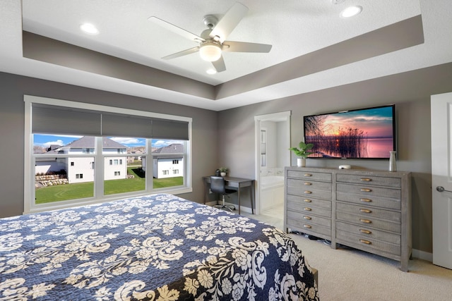 bedroom featuring carpet floors, a ceiling fan, a tray ceiling, and ensuite bathroom