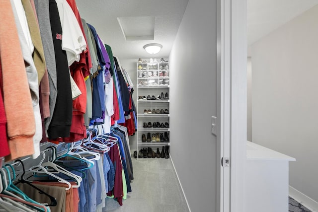 walk in closet with light colored carpet and attic access