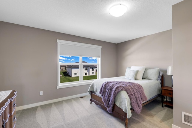 bedroom with baseboards, visible vents, and light carpet
