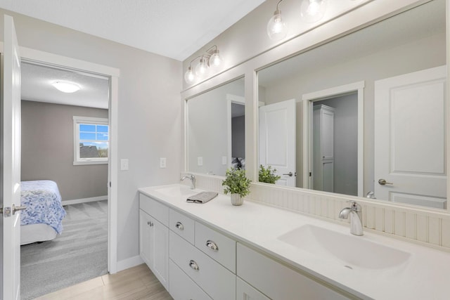 full bath with double vanity, baseboards, a sink, and ensuite bathroom