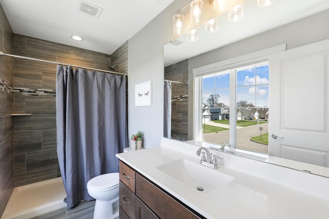 bathroom featuring vanity, toilet, recessed lighting, visible vents, and tiled shower