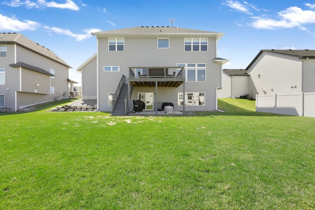 back of property with a lawn, a wooden deck, and stairway