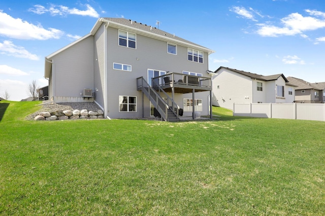 back of property with a lawn, a wooden deck, and stairs