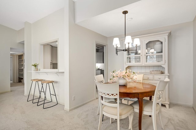 dining room featuring baseboards, an inviting chandelier, and light colored carpet