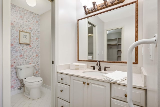bathroom featuring tile patterned floors, wallpapered walls, vanity, baseboards, and toilet