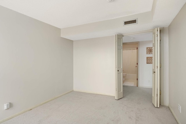 spare room featuring light colored carpet, baseboards, and visible vents