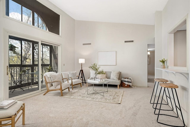 living room featuring carpet floors, visible vents, and a high ceiling