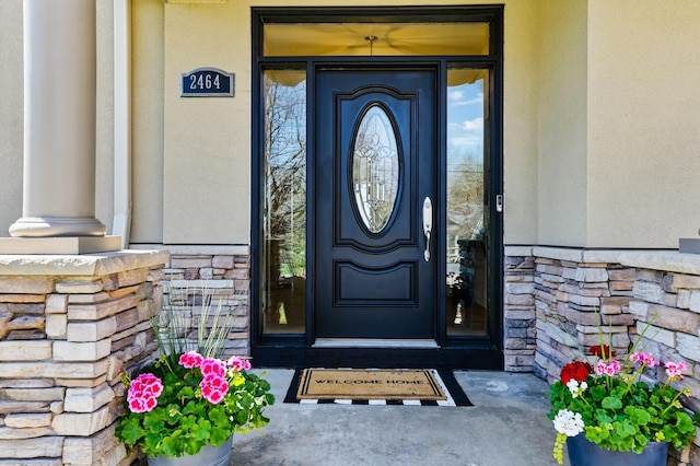 entrance to property featuring stucco siding and stone siding