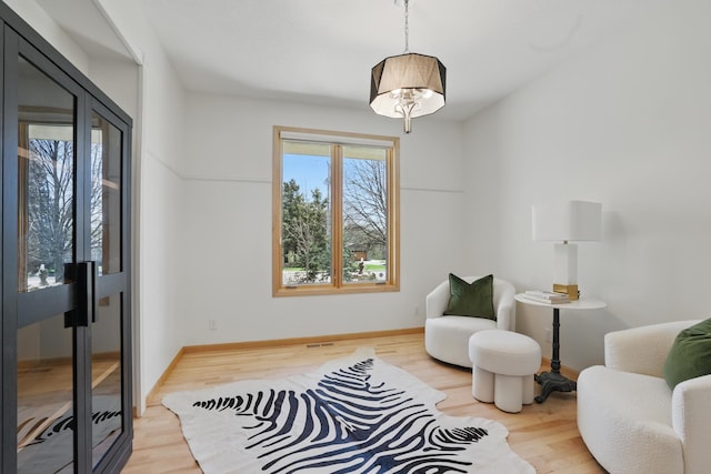 living area with baseboards, wood finished floors, and visible vents