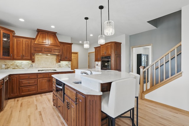 kitchen featuring oven, a sink, light wood-style flooring, custom range hood, and a kitchen bar