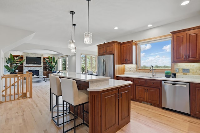 kitchen featuring decorative backsplash, a breakfast bar area, a sink, light countertops, and stainless steel appliances