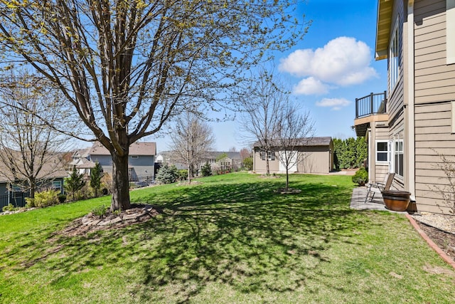view of yard featuring a residential view, an outdoor structure, and a balcony